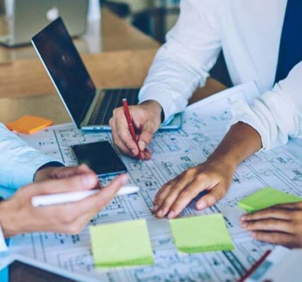 Cropped image of male and female engineer professionals cooperating togetherness near desktop analyzing information for building project, young crew creating sketches during working time in company