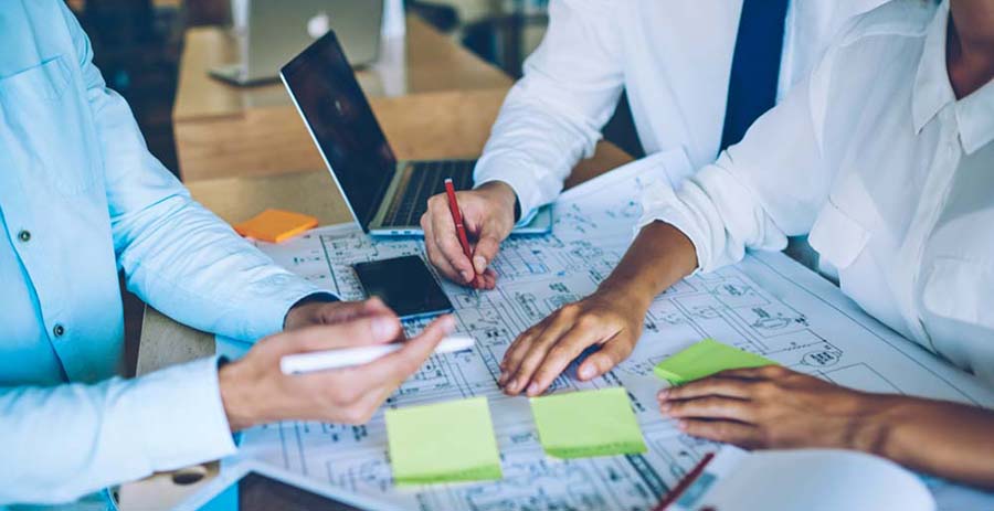 Cropped image of male and female engineer professionals cooperating togetherness near desktop analyzing information for building project, young crew creating sketches during working time in company